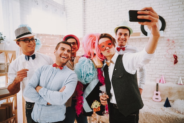 Personas con pajaritas tomando selfie en teléfono en la fiesta.