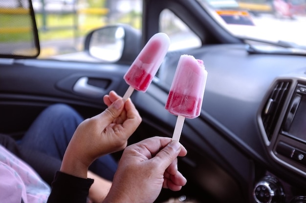 Personas con palitos de helado rosa en el auto