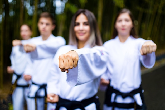 Personas patadas altas durante el entrenamiento de taekwondo al aire libre fondo de bambú