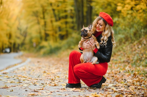 Personas y perros al aire libre. Mujer hermosa y feliz disfrutando en el parque otoño caminando con su adorable bulldog francés.