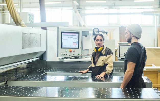 Personas de pie en la máquina en la fábrica.