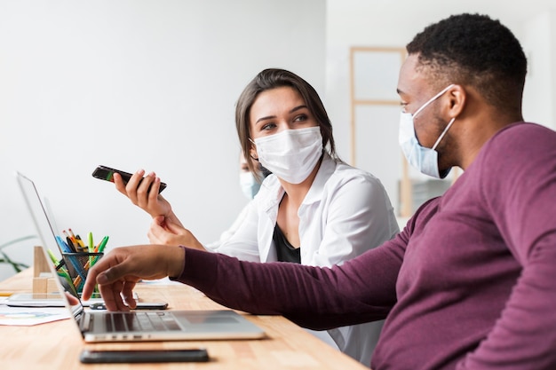 Personas que interactúan en la oficina durante una pandemia con máscaras