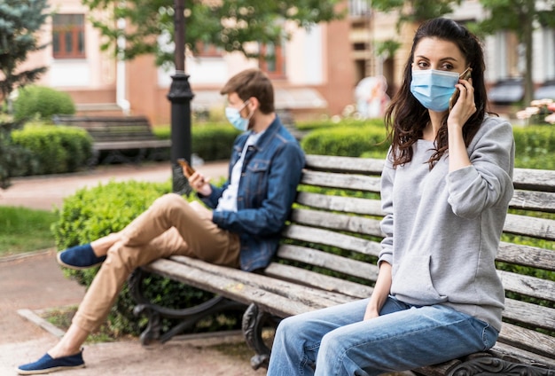 Foto personas que respetan la distancia social sentadas en un banco