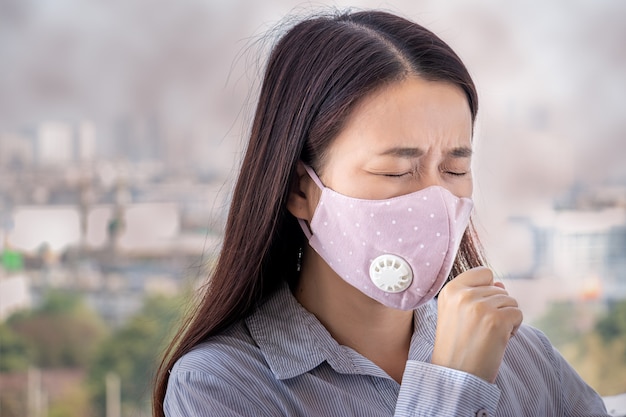 Foto las personas que se sienten enfermas por la contaminación del aire, el medio ambiente tiene efectos nocivos o venenosos. mujer en la ciudad con mascarilla para protegerse