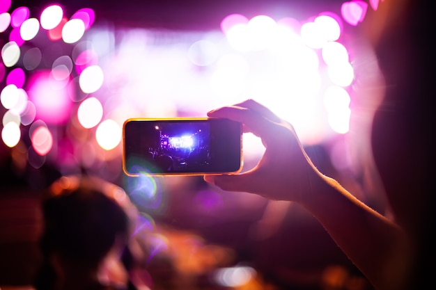 Las personas que toman fotografías con el teléfono inteligente durante el concierto de música en vivo y la multitud