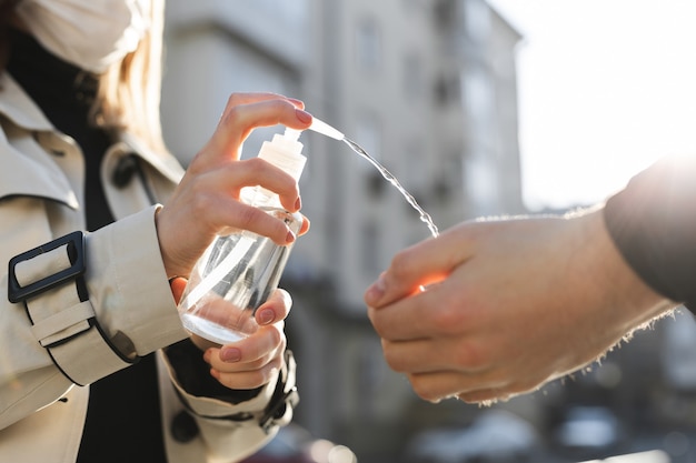 Personas que usan gel antiséptico a base de alcohol y usan una mascarilla preventiva.