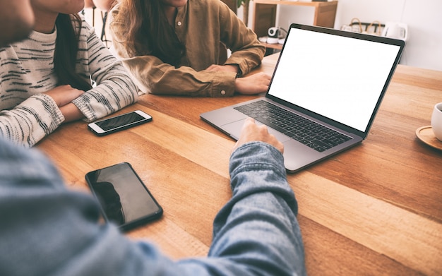 Las personas que usan y miran la computadora portátil maqueta en una mesa de madera juntos