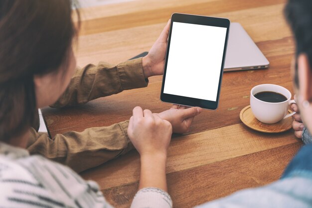 Personas que usan y miran la misma maqueta de tablet pc en la mesa de madera juntos