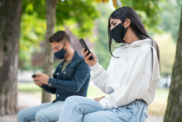 Personas que usan un teléfono móvil en el parque durante la pandemia de coronavirus