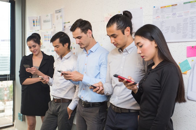 Las personas que usan teléfonos inteligentes para trabajar juntos en el lugar de la oficina.