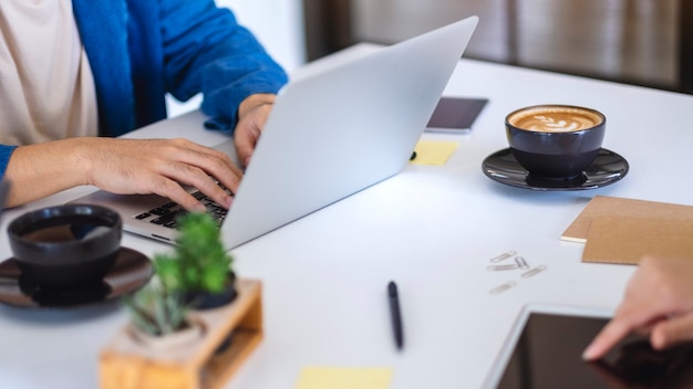 Personas que usan y trabajan en computadoras portátiles y tabletas en la mesa en la oficina