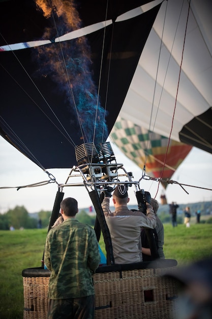 Personas sentadas en la canasta y calentando el globo sacándolo en el aire