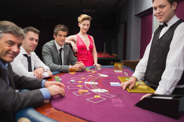 Personas sentadas en la mesa de blackjack y sonriendo