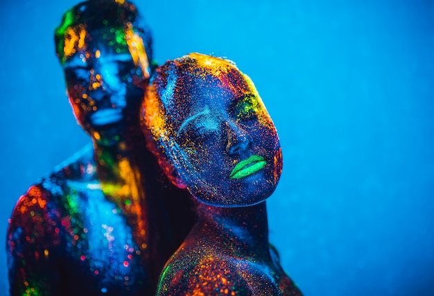 Las personas son polvos fluorescentes de colores. Una pareja de enamorados bailando en una discoteca.