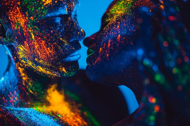 Las personas son polvos fluorescentes de colores. una pareja de enamorados bailando en una discoteca.