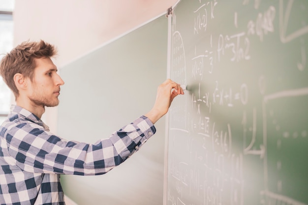Las personas sostienen la mano con tiza y escriben cálculos matemáticos en un tablero b
