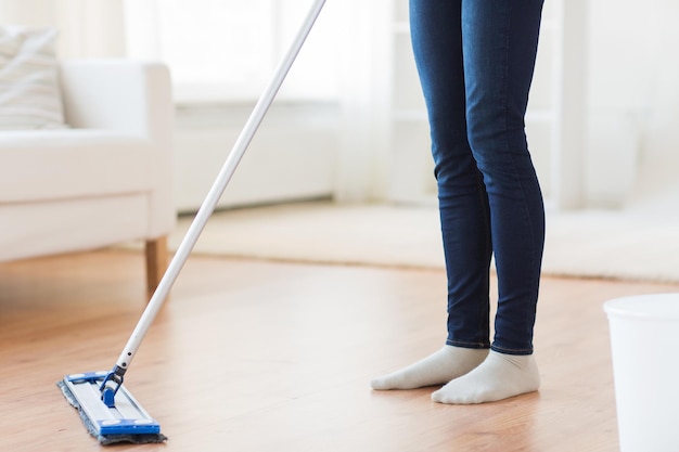 personas, tareas domésticas y concepto de limpieza - cierre de piernas de mujer con piso de limpieza de mopa en casa