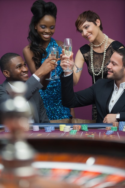 Personas tintinean vasos en la mesa de ruleta