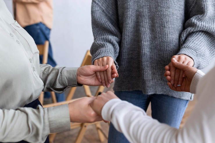 Foto personas tomadas de la mano en una sesión de terapia de grupo