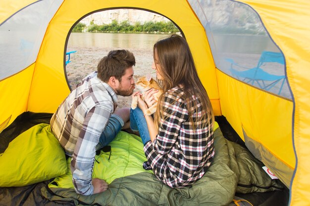 Personas, turismo de verano y concepto de naturaleza - pareja joven descansando en la tienda de campaña, vista desde el interior.