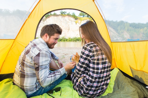 Personas, turismo de verano y concepto de naturaleza - pareja joven descansando en la tienda de campaña, vista desde el interior.