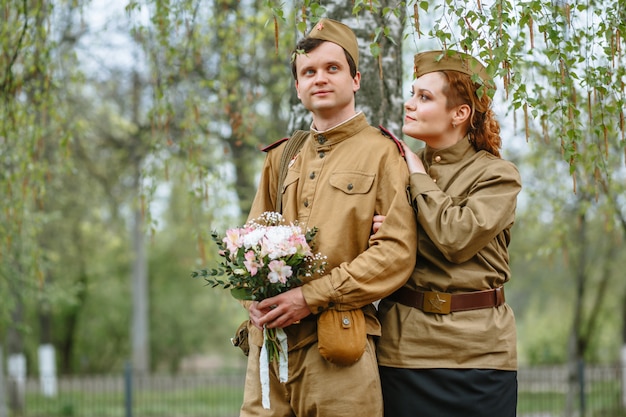 Personas con uniformes militares soviéticos. Una pareja está parada junto a un árbol