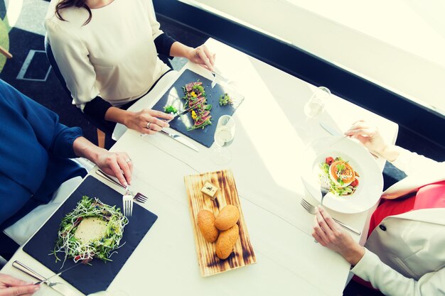 personas, vacaciones, celebración y concepto de estilo de vida - cerca de mujeres comiendo aperitivo para cenar en el restaurante