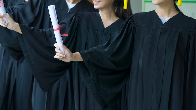 las personas con vestidos de graduación negros tienen diploma.