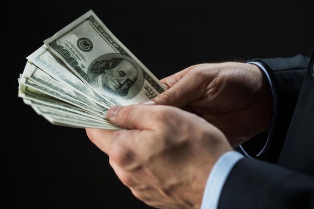 Personen-, Geschäfts-, Finanz- und Geldkonzept - Nahaufnahme von Geschäftsmannhänden, die Dollar-Bargeld auf schwarzem Hintergrund halten