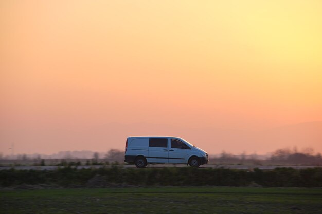 Personenwagen, der bei Sonnenuntergang schnell auf der Überlandstraße fährt Autobahnverkehr am Abend