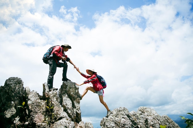 Personenwanderungsfreunde, die sich gegenseitig auf einen Berg helfen Mann und Frau, die eine helfende Hand geben