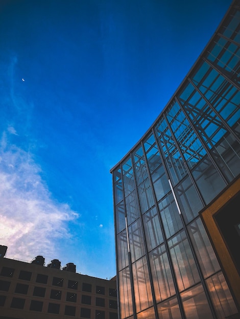 Perspectiva hacia arriba de una fachada de vidrio y una luna creciente