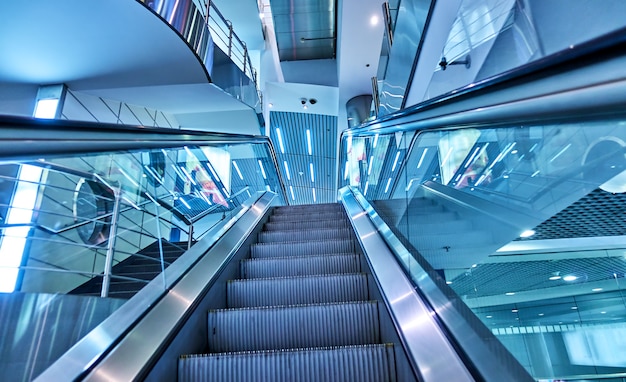 Perspectiva de escaleras mecánicas en la terminal del aeropuerto. Entonado en azul