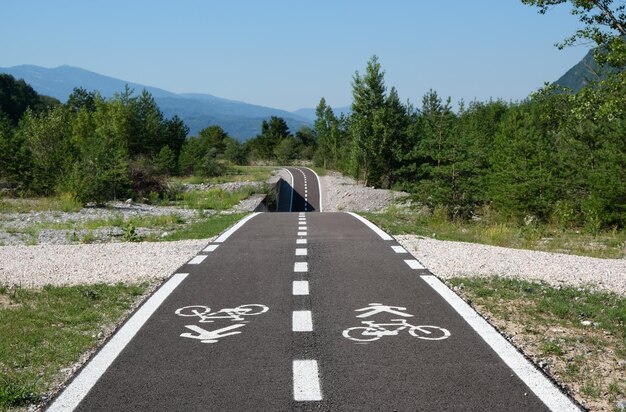 Perspektive eines Radwegs inmitten von Bäumen gegen den Himmel