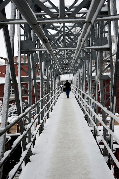 Perspektivische Ansicht einer Metallbrücke, die eine Eisenbahnlinie überquert.