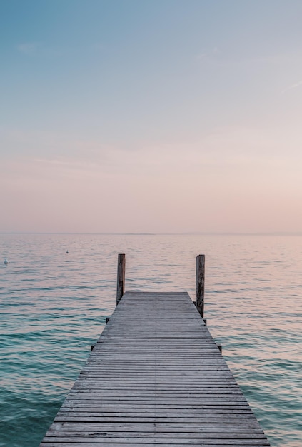 Perspektivischer blick auf einen holzsteg an der küste mit klarem morgenhimmel und meer mit türkisfarbenem wasser