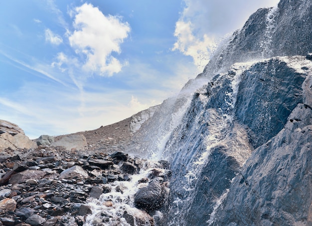 Perto da água que flui de uma geleira em uma parede rochosa em uma montanha alpina