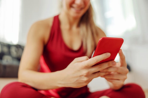 Perto da desportista sentada no chão e usando o telefone inteligente.