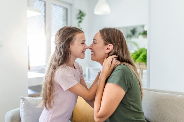 Perto da doce linda filha, abraçando sua jovem mãe. Linda mãe abraçando sua filha no sofá em casa.