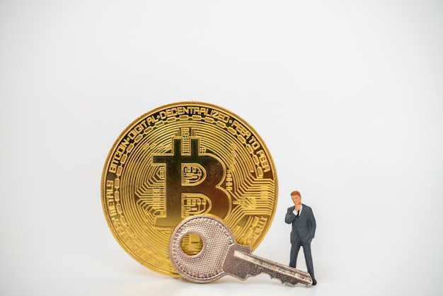 Perto da figura em miniatura de um empresário, com moedas de ouro bitcoin e chave de prata