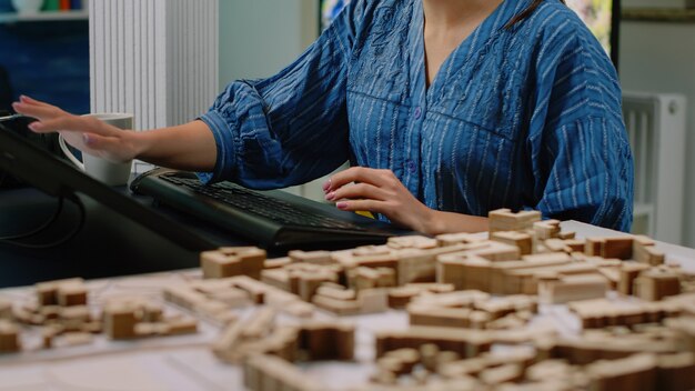 Perto da mesa de arquitetura com o modelo de construção e o computador