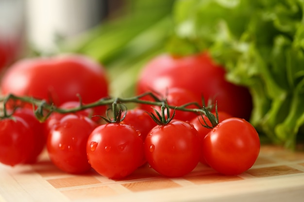 Perto da mesa de madeira com deliciosos tomates frescos com gotas de orvalho