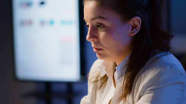 Perto da mulher gerente estressada massageando os olhos cansados enquanto está sentado no local de trabalho, no escritório start-up, fazendo hora extra na frente do laptop ol. empresária trabalhando demais para respeitar o prazo.