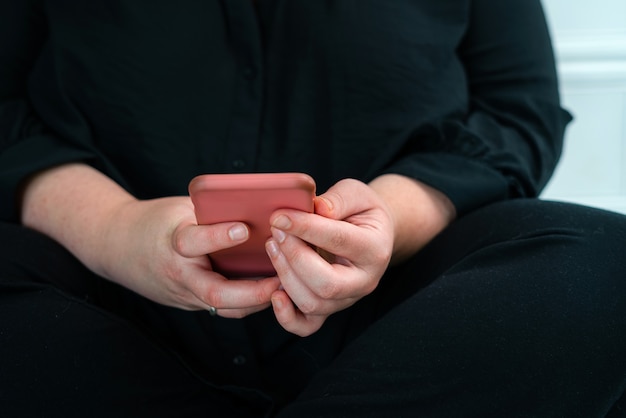 Perto da mulher lendo notícias no telefone inteligente em casa. Mensagens de texto de mãos ou rolagem nas redes sociais. Navegar na internet, bater papo online