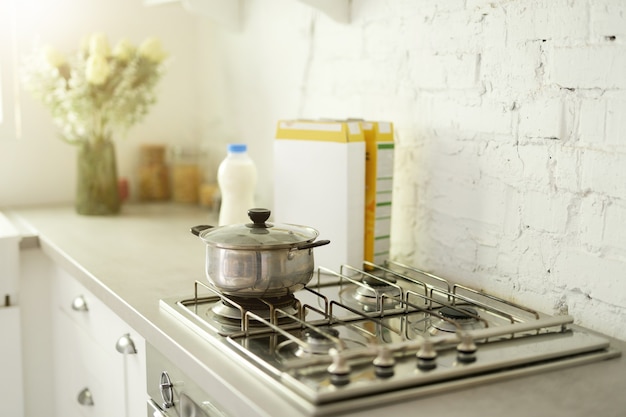 Perto da panela de aço inoxidável no fogão a gás na cozinha moderna contemporânea. foco seletivo. bom dia, cozinhando o conceito do café da manhã