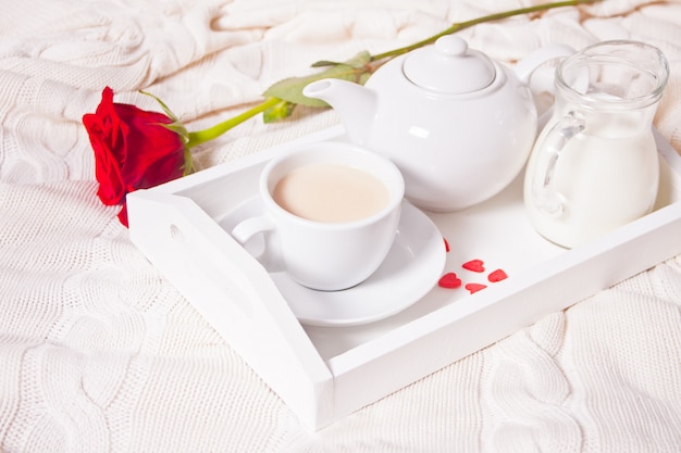 Perto da xícara de chá com rosa vermelha na bandeja branca