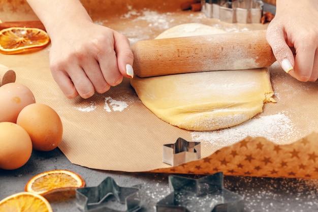 Perto das mãos da mulher preparando massa para biscoitos