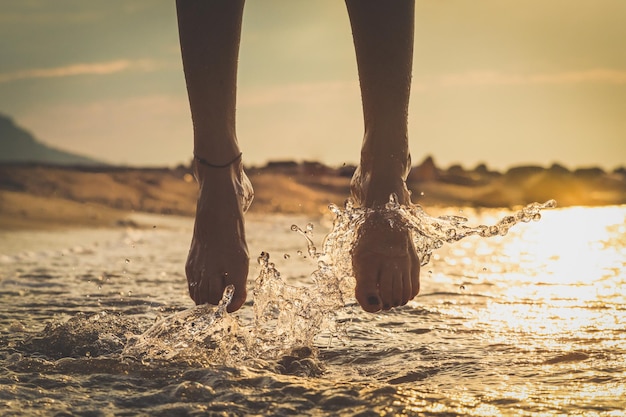 Perto das pernas de uma rapariga enquanto ela salta na água do mar