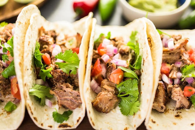 Perto de carnitas de porco desfiada com pico de gallo em uma tortilha de farinha.