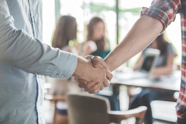 Foto perto de dois jovens parceiros de negócios, apertando a mão em um café